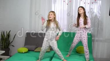 两个穿着睡衣的<strong>小女孩</strong>在沙发上<strong>跳舞</strong>
