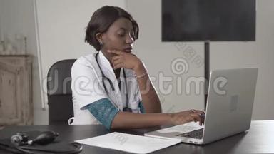 黑人女医生坐在办公桌前看镜头，非裔美国人护士在<strong>柜子</strong>里的笔记本电脑上工作，现代