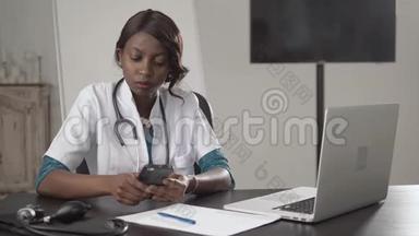 黑人女医生坐在办公桌前看镜头，非裔美国人护士在柜子里的笔记本电脑上工作，现代