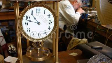 老式扭摆钟摆在桌子上，而钟表学家则在后台工作