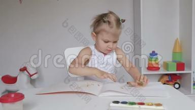 坐在桌子旁的小可爱女孩在相册里画画