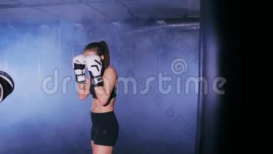 年轻女子拳打脚踢拳击馆的拳击手套