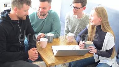 一群快乐的朋友或同事在一家小咖啡馆里喝着咖啡，笑着一起用电脑