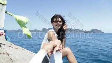 美丽的女人坐在泰国的船上牵着男人的手快乐的微笑