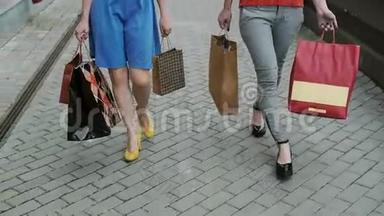 快乐的年轻女孩朋友带着购物袋走过商店，谈笑风生。 缓慢的莫史泰康射击