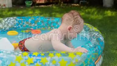 快乐的微笑幼儿男孩在花园草地上玩充气游泳池