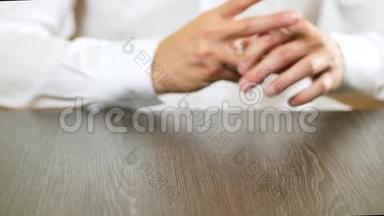 一个穿白色衬衫的人从手指上摘下订婚戒指。 关于离婚的决定。