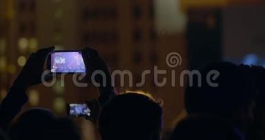 观众在室外音乐音乐会上通过智能手机录制舞台和大屏幕变焦视频