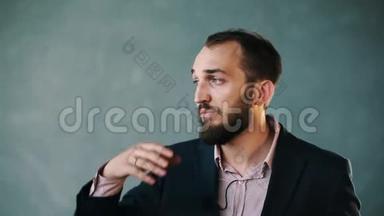 穿着夹克和条纹衬衫的大胡子男人在隔离墙上讲话时打手势