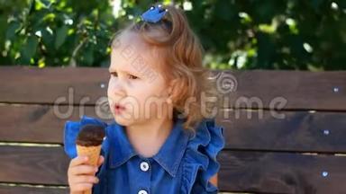 小女孩在阳光明媚的夏天在公园里吃冰淇淋和巧克力。 婴儿特写肖像