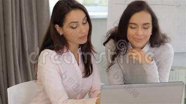 两个女人在办公室讨论笔记本电脑上的东西