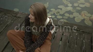 年轻女子坐在<strong>木墩</strong>上的湖边。