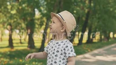 戴帽子的小孩子捕捉泡泡。 小男孩夏天在外面玩