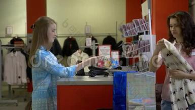 两个快乐的年轻女孩正在百货公司的一个收银台买衣服。