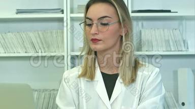 戴眼镜的漂亮女医生用笔记本电脑坐在<strong>前台</strong>