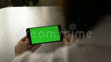女人拿着一部绿色屏幕的手机。 供你的视频内容..