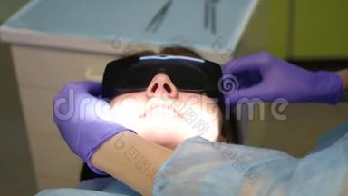 带着干细胞学家的女孩戴着特殊的防护眼镜检查牙齿。 4k. 3840x2160