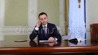 一个商人坐在办公室的时候，看上去很累，用手机说话