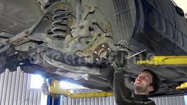 熟练的机械师在<strong>汽车</strong>下面的车库中拆卸磨损的<strong>汽车部件</strong>。