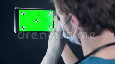 男医生拿着绿色屏幕浏览数字平板电脑。