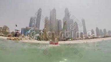 这个女孩沐浴在<strong>大海</strong>中，在迪拜摩天大楼的<strong>背景</strong>下喷水。 慢速射击。