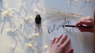 女艺术家的手写钢笔字体与书法字母在桌子上闪烁花环在工作室。