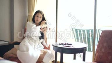 酒店客房内，坐在椅子上为自己化妆的快乐女人浴袍