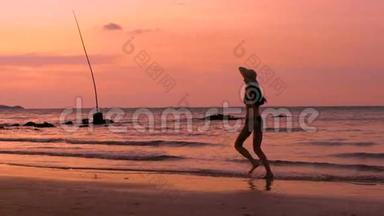 度假日落时，戴帽子的快乐女人在海滩上奔跑的慢<strong>动作剪影</strong>