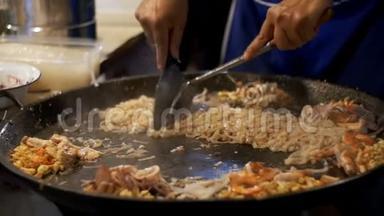 亚洲街的食物。 海鲜，米粉用鸡蛋煮在大煎锅上.. 动作缓慢。 泰国
