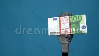 一只机械手握着一捆欧元。 一只灰色的半机人手在蓝色背景上拿着钱。