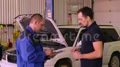 <strong>汽车修理工</strong>在车库里和车主一起测试<strong>汽车</strong>时使用小工具