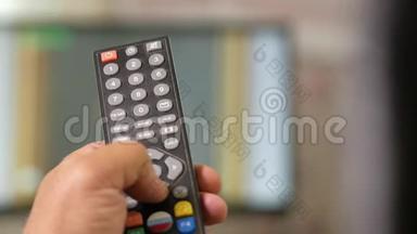一个人`手握着电视上的遥控器，开关频道。 特写镜头，移动摄像机