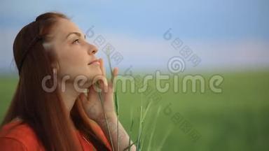 晚上，一个红发的年轻美女站在一片绿<strong>麦子</strong>的田野里，把麦穗放在她的地里