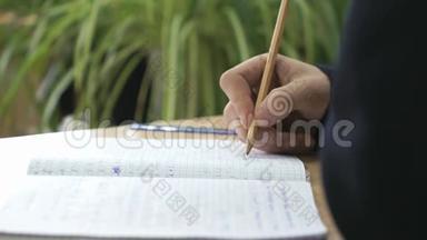女生用铅笔在笔记本上写课文