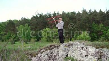 英俊的男孩在岩石上玩玩具飞机。 4k