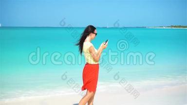 年轻女子在热带海滩度假<strong>时使用</strong>电话。 <strong>使用</strong>移动智能手机的游客。