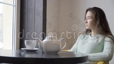 黑发女孩坐在咖啡馆里<strong>看着窗外</strong>。