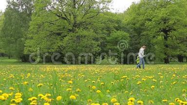 一个带着孩子的年轻女人正带着蒲公英在田野里走来走去。