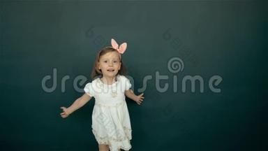 可爱快乐的<strong>小女孩跳舞</strong>。 在绿色背景上，微笑的儿童肖像。