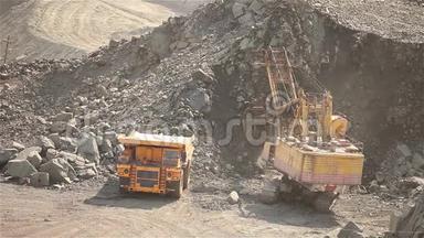 采石场的挖掘机和翻斗车，挖掘机在翻斗车内装载原材料，在铁矿石采石场工作。