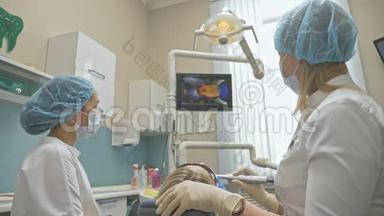 医生用特殊的口腔检查数字微相机检查牙齿。 监控牙医和病人看录像
