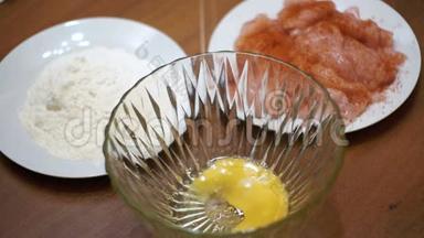 在家庭厨房里的面粉和肉的背景下，碎蛋<strong>落入</strong>透明碗中。 慢动作