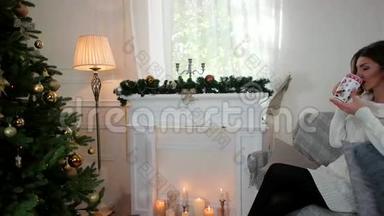 一位年轻女子喝茶的肖像，在圣诞树附近的客厅里，快乐的女孩喝茶，微笑的样子