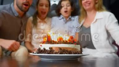 快乐的微笑男孩在她的<strong>生日蛋糕</strong>上吹蜡烛。 被家人包围的孩子。 有蜡烛的<strong>生日蛋糕</strong>
