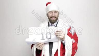 穿着圣诞老人套装的商人拿着一张纸，上面写着数字。 最后倒数