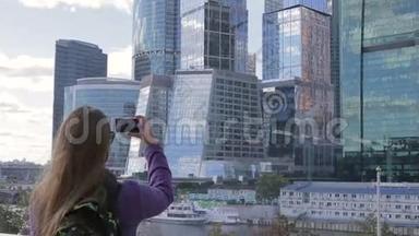 年轻女子用智能<strong>手机手机</strong>摄像头<strong>拍摄</strong>了一张高楼的照片。