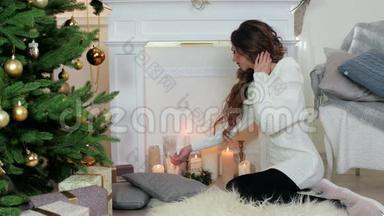 点燃蜡烛，穿着温暖舒适毛衣的美丽年轻女子点燃了壁炉旁的蜡烛