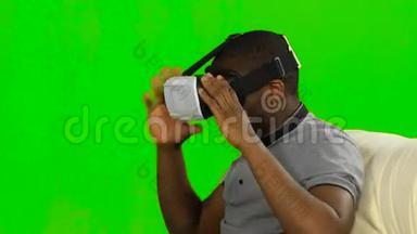 男人戴着VR面具看电影吃爆米花。 绿色屏幕