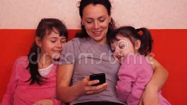 妈妈和女儿玩手机。 幸福的家庭玩手机。