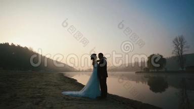 婚礼当天晚上，两对新婚夫妇在夕阳下浪漫的湖边拥抱